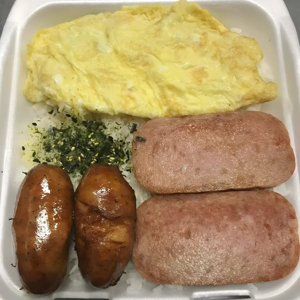 Poke Etc. plate lunch with omelet, spam, sausages, rice, and furikake in a styrofoam container.