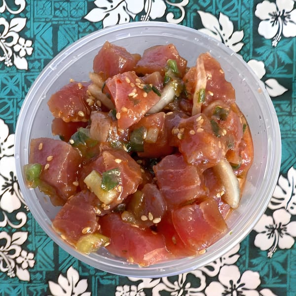 A clear plastic container filled with Poke Etc's fresh poke, featuring cubed tuna, onions, and sesame seeds.